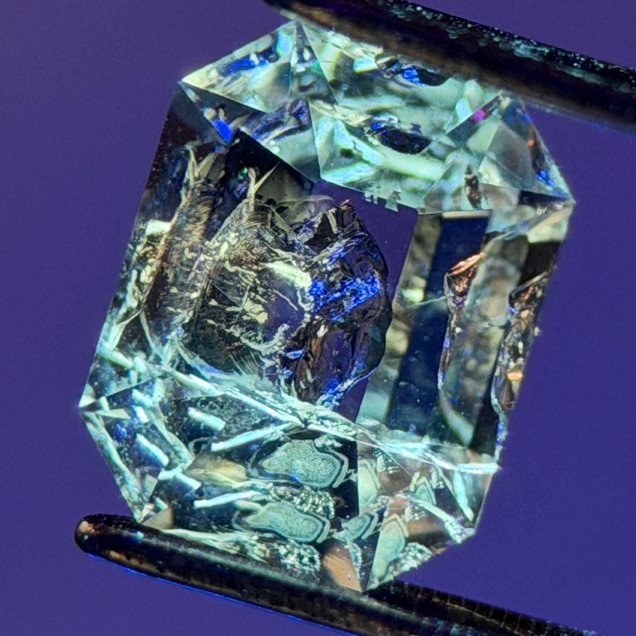 天然石油水晶 – 0.75 克拉八角形切割 (4.9 x 6.3 毫米) – 彩虹光暈與黑色礦物