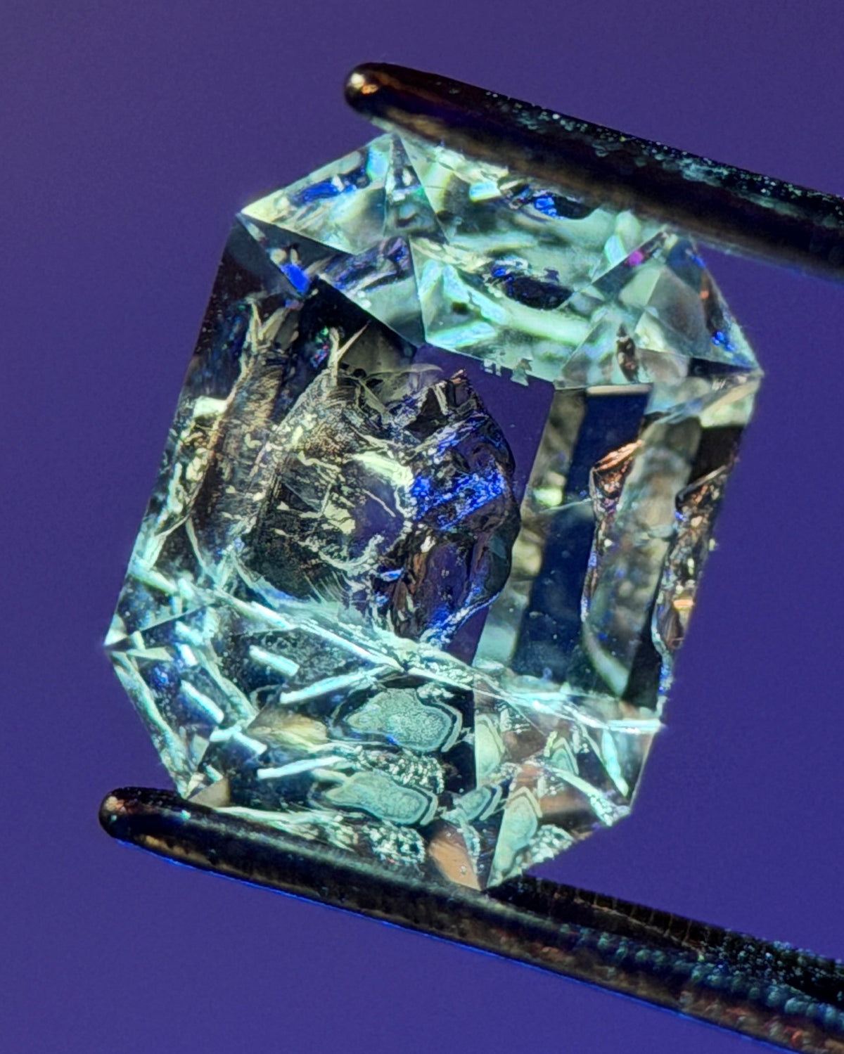 天然石油水晶 – 0.75 克拉八角形切割 (4.9 x 6.3 毫米) – 彩虹光暈與黑色礦物